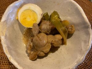 A close-up of chicken drumsticks and boiled eggs cooked in a savory vinegar sauce with green onions, prepared in an auto cooker.