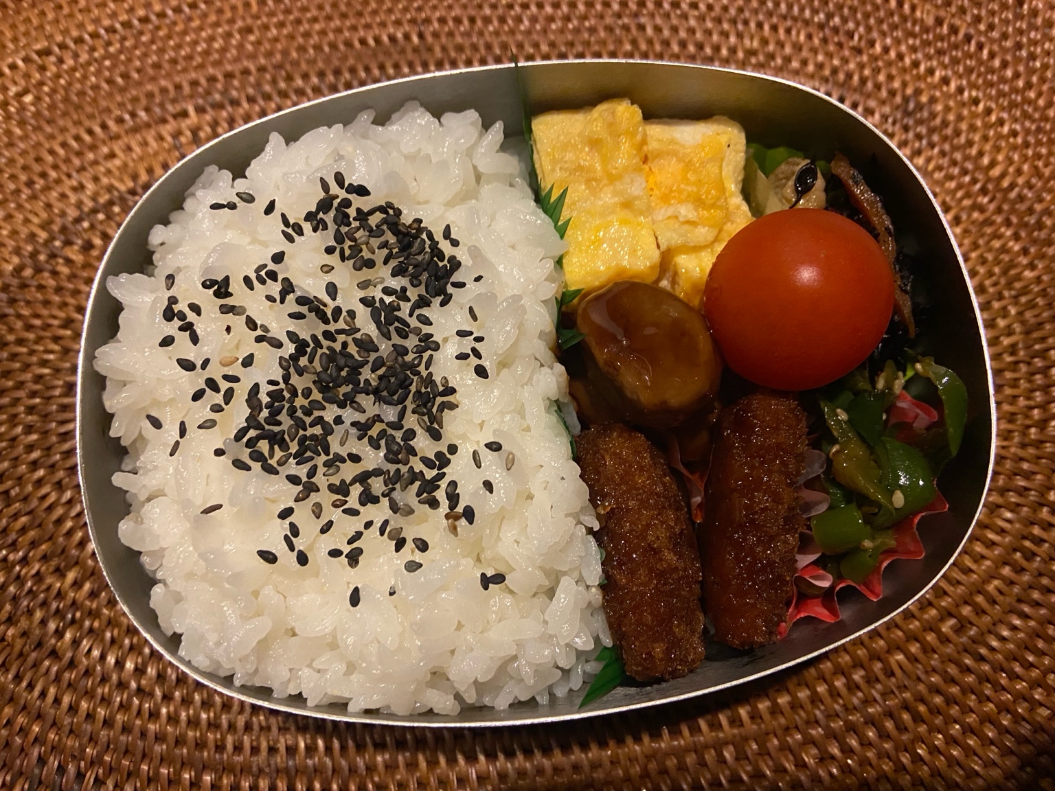 A Japanese bento box with rice, tamagoyaki, mini sausages, vegetables, and fried items, prepared for a midweek lunch.