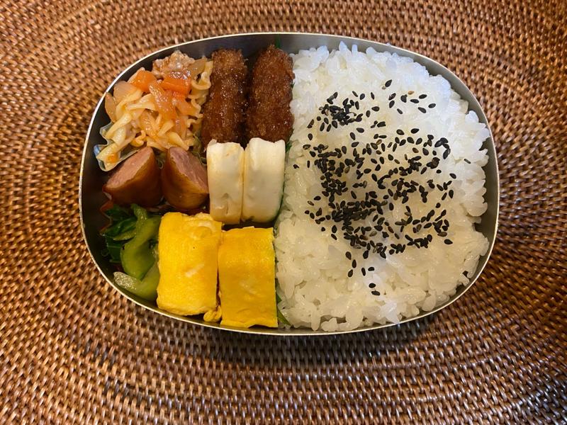 A Japanese bento box with rice, tamagoyaki, mini sausages, vegetables, and fried items, prepared for a midweek lunch.