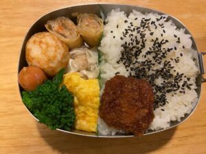 A traditional Japanese bento featuring rice balls, fried items, and vegetables.